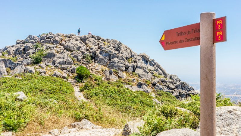 steinhaug, h�yde med 2 mennesker og et veiskilt som peker i den retningen