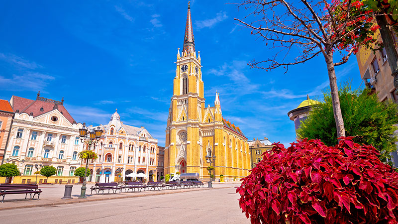 Stor kirke ved en �pen plass i Novi Sad. Tr�r og benker i ulike farger. 