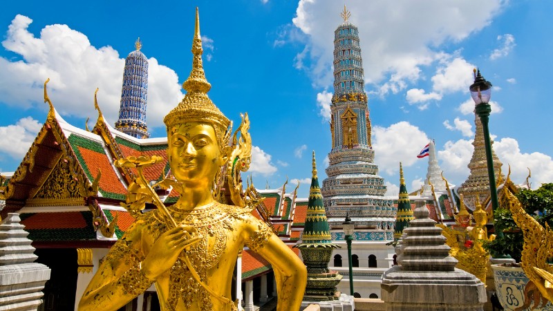 Buddha figur i gull og byggverk i bakgrunn