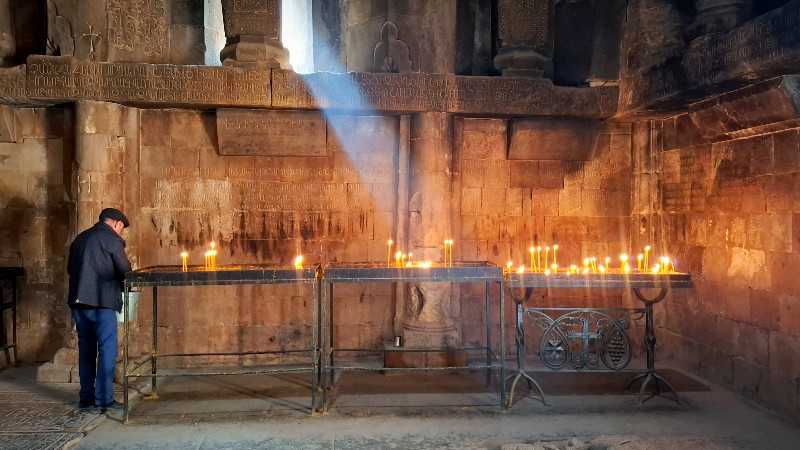 En mann st�r ved tente stearinglys inn klosteret