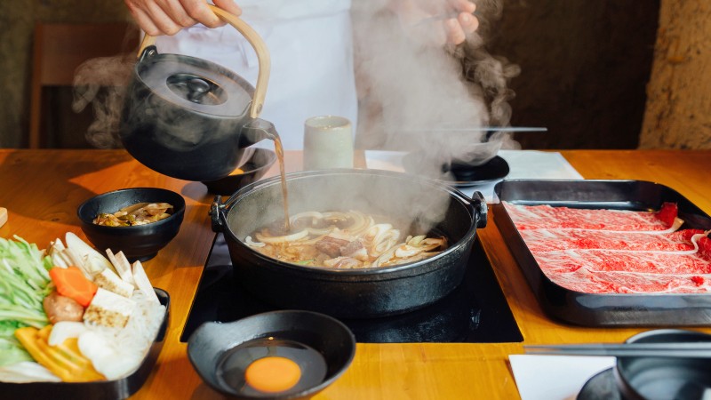 En kokk heller soyasaus over stekte gr�nnsaker i en varm kjele 