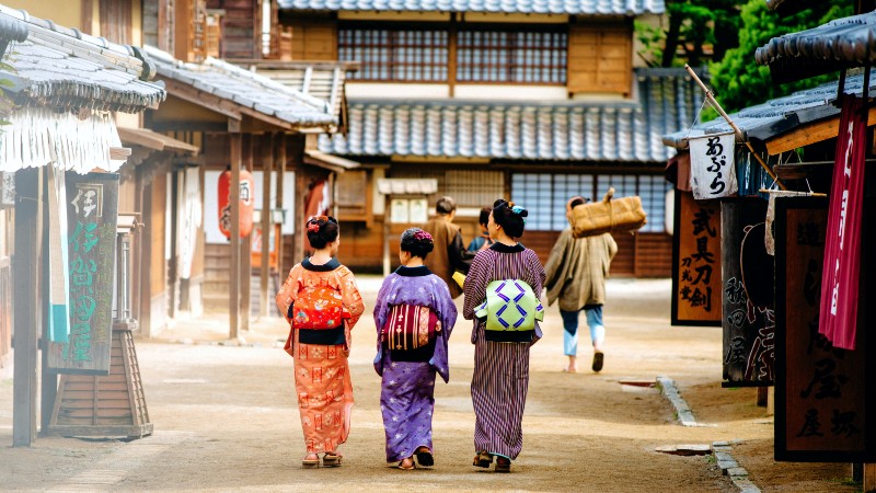 Tre kvinner i tradisjonelle antrekk g�r ned en gate