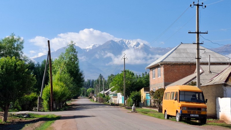 Tom vei i landsbyen Kyzyl-Tuu, med h�ye sn�kledde fjell i bakgrunnen