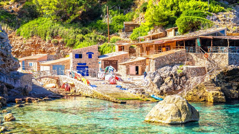 Liten havn med steinhus og krystallklart vann p� Mallorca