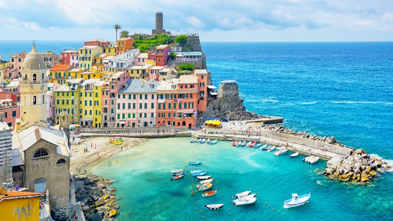 Bygninger, kirke, flotte farger, b�ter, hav og en molohavn og mange mennesker.