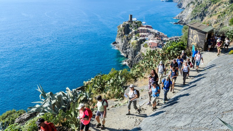 Mange mennesker som g�r p� en grussti med havet rett ut